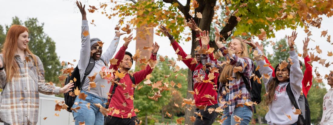 A group of students throwing fall leaves