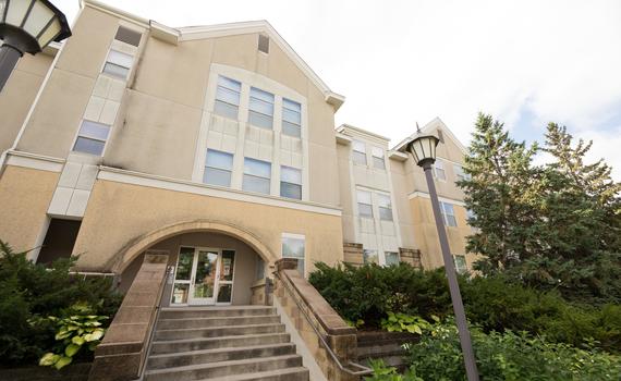 The front of Hamline University Apartments, with a short staircase and two streetlamps