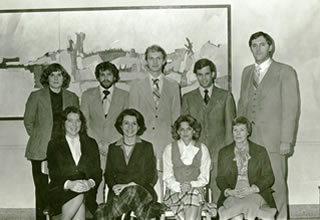A black and white photo of a group of people standing in front of a painting from the Hamline Archives