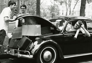 A group of unidentified Hamline students in 1965 packing many boxes inside of a Beetle car
