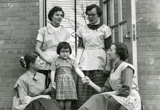 A group of unidentified women surrounding a child from the Hamline archives