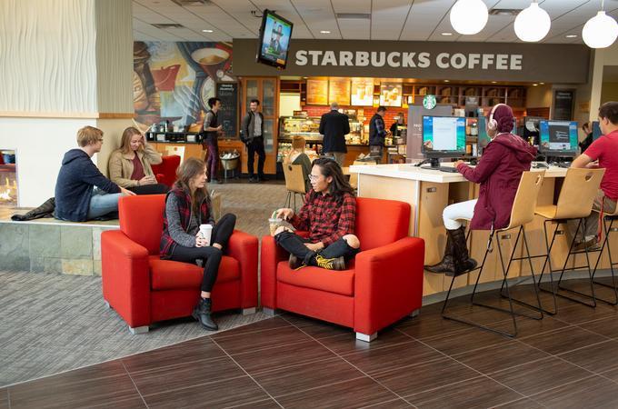 Hamline studnets sitting in a chair in front a starbucks coffee store at Hamline.
