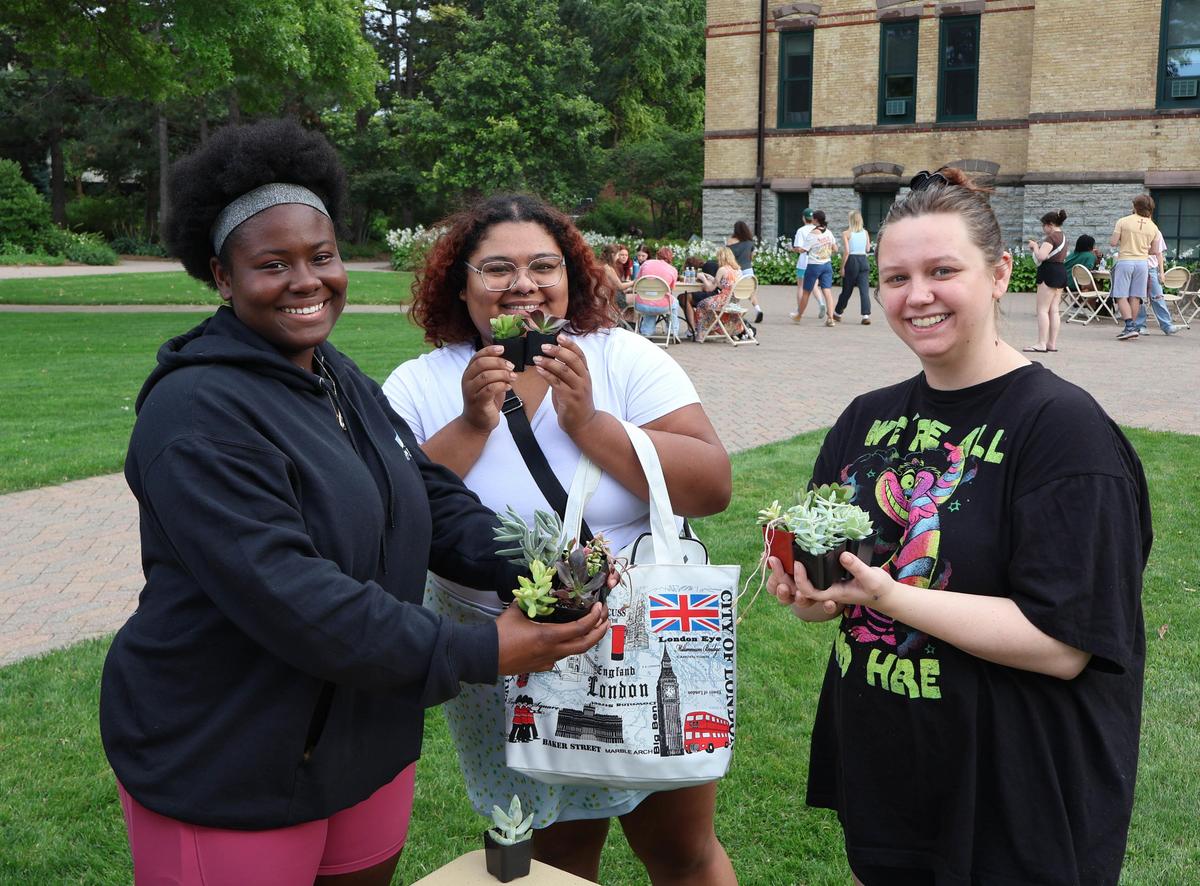 Three students holding plants for Adopt a Plant event