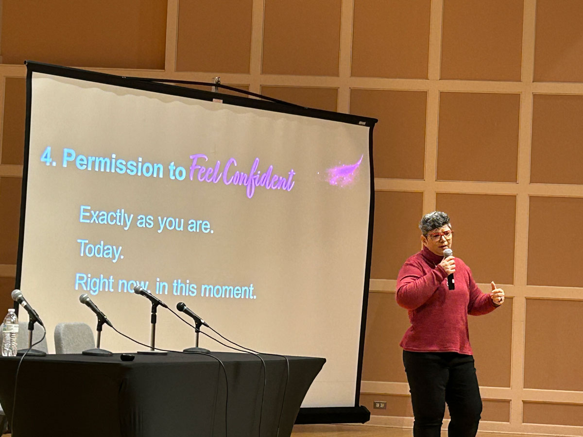 Women in Public Service (WIPS) speaker in front of screen reading "Permission to feel confident"