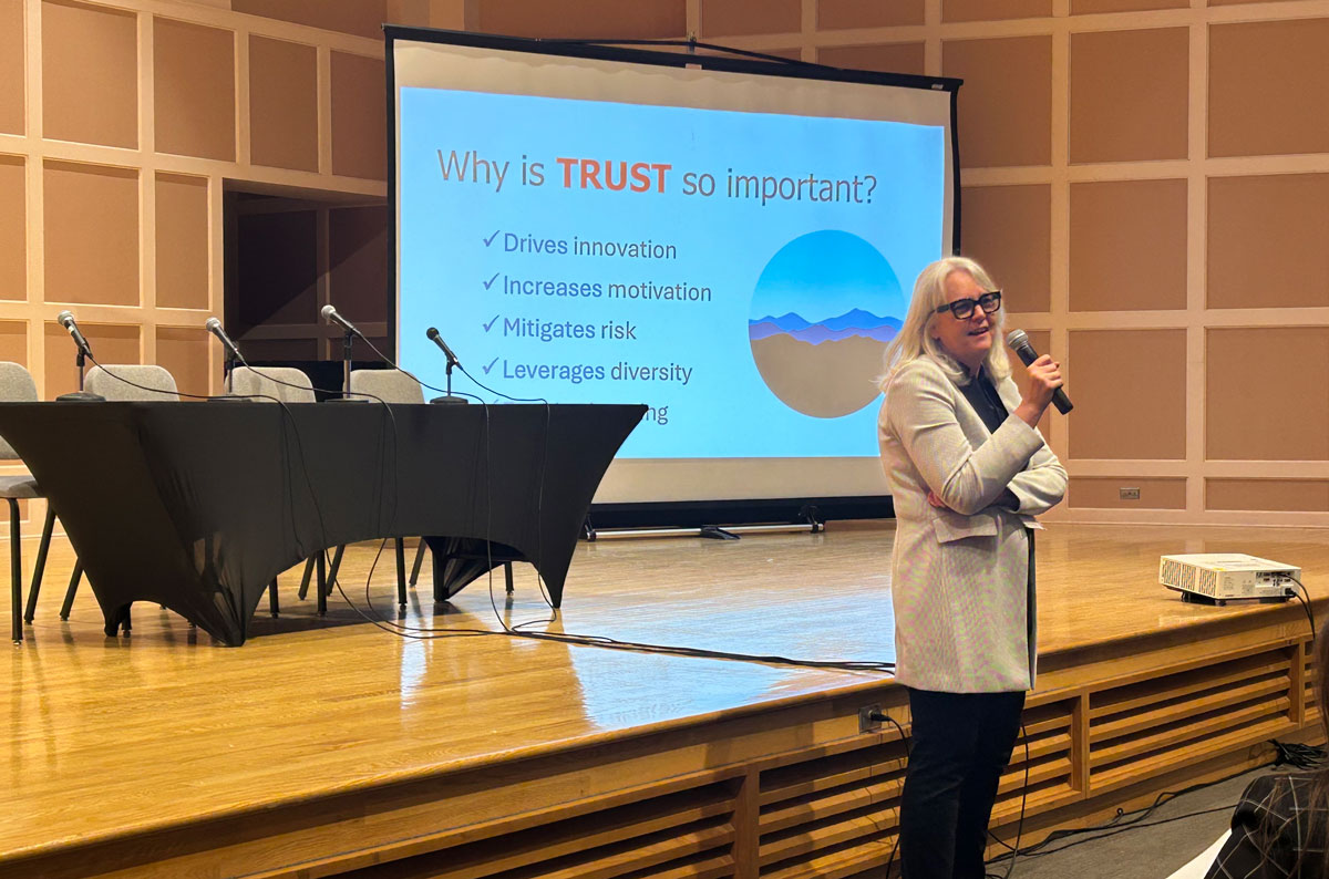 Speaker at the Women in Public Service (WIPS) Conference in front of screen reading "Why Trust is Important"