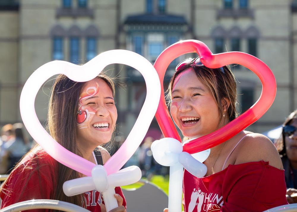 Two students laughing with heart-shaped balloons