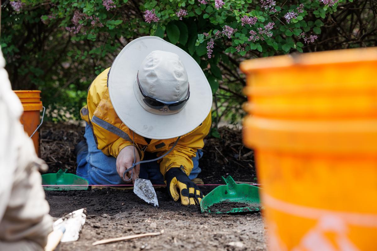 Student using small trowel to dig in anthropology class