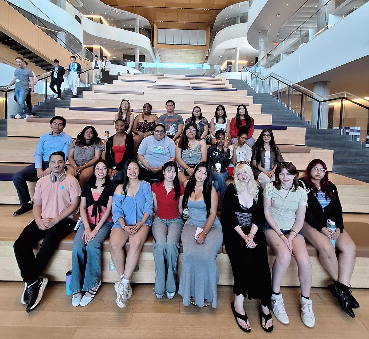 Large group of TRiO students sitting on the stairs inside a library on a college campus