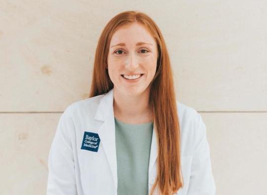 Physician assistant student Kristen Berry wearing a white coat smiling at the camera