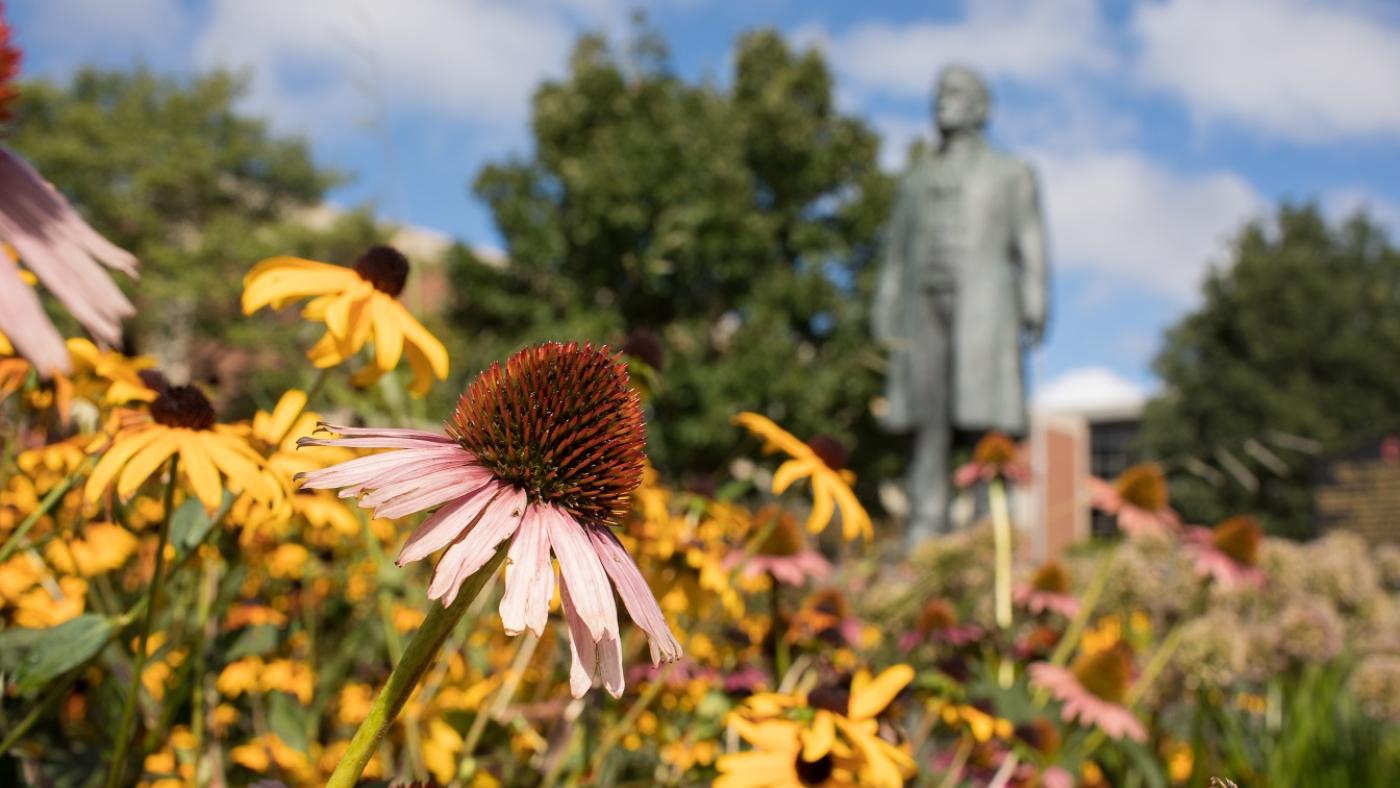 Flowers bloom near the Bishop Hamline statue