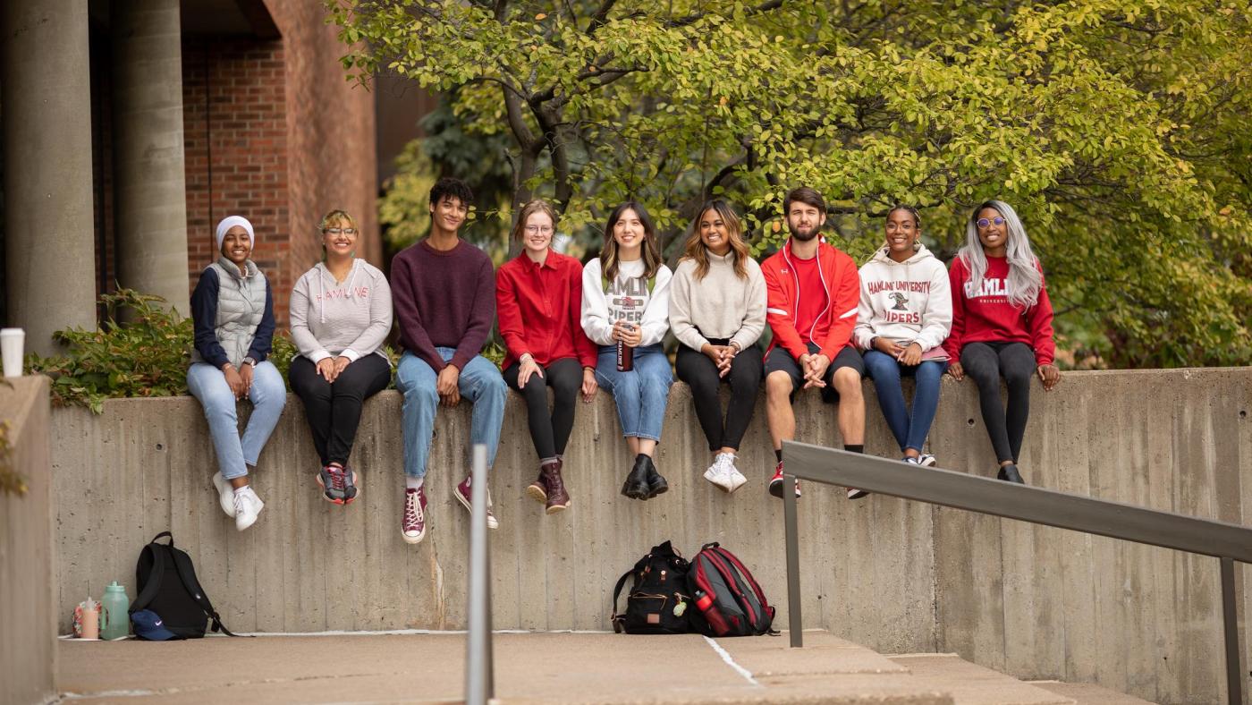 Hamline students sitting on a wall
