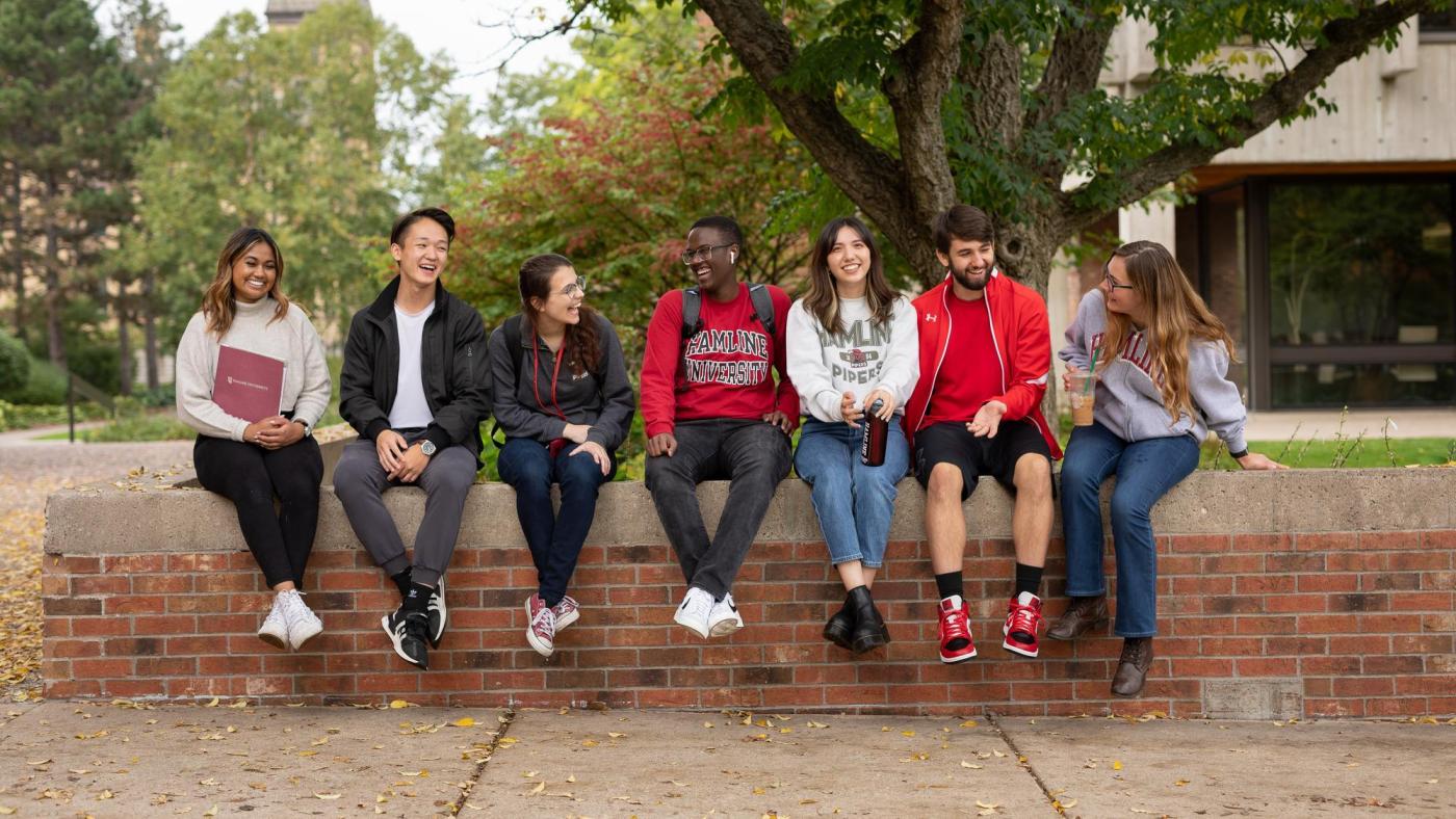 Students sitting on wall on campus