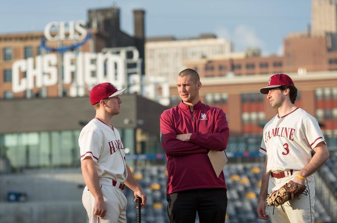 Coach and two Hamline students in a baseball field 