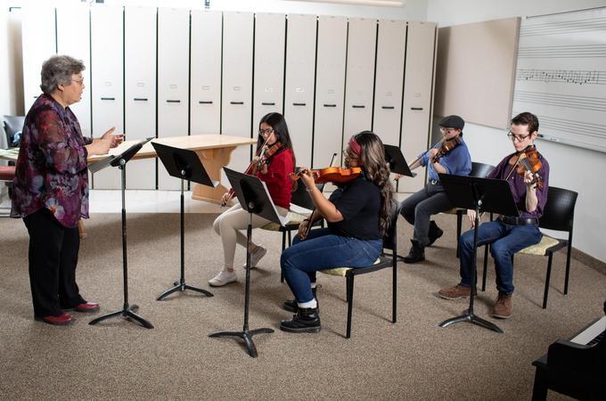 A music professor instructing a quartet of student strings in a Hamline classroom