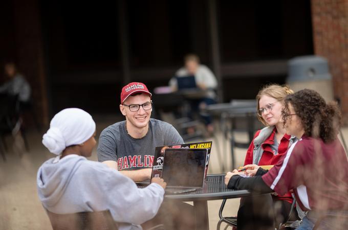 Students study on an outdoor patio with their laptops