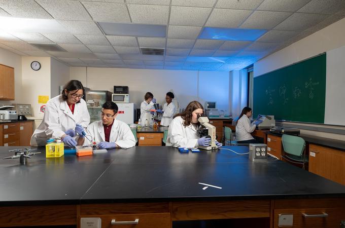 A professor and students work in a science lab