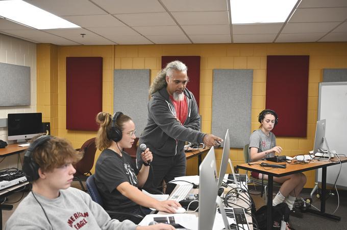 A professor assists students in a music production classroom