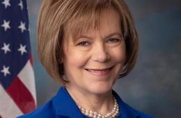 Headshot of Senator Tina Smith standing in front of flag