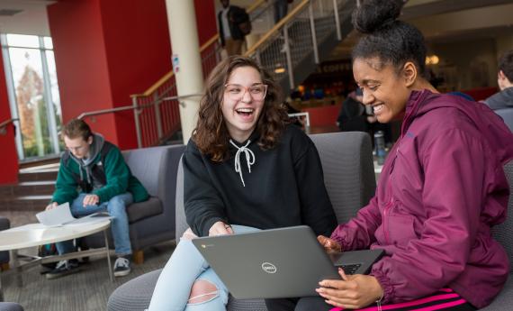 Two transfer students on Anderson Center talking with each other looking at a computer