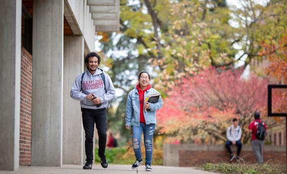 Two international graduate students happily engaging with each other on campus 