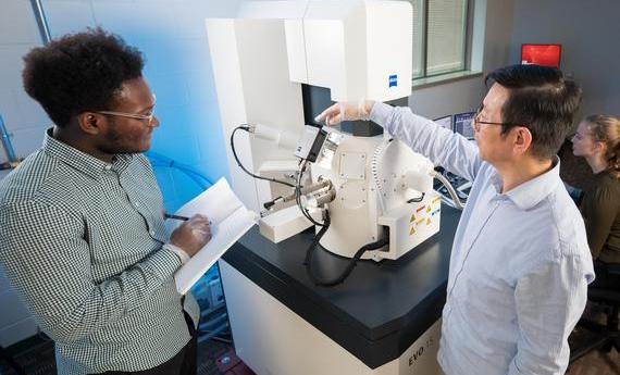 Two people using an electron microscope in Hamline's College of Liberal Arts