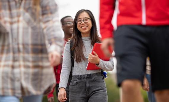A smiling Hamline international student walking in a group of students on campus