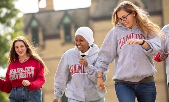 Three Hamline students walking on campus and smiling