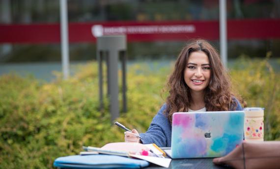 Smiling Transfer students looking to her computer at Hamline University