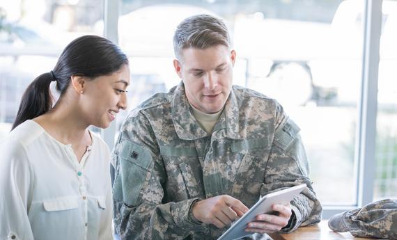 A  man military student with another woman looking into an Ipad
