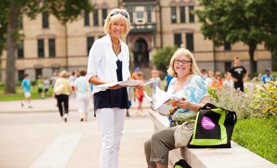 Two older women holding booklets and looking at the camera