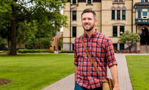 A Hamline graduate student walking outside of Old Main on campus