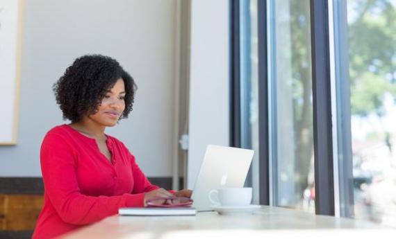 A person sitting at home on their laptop, smiling