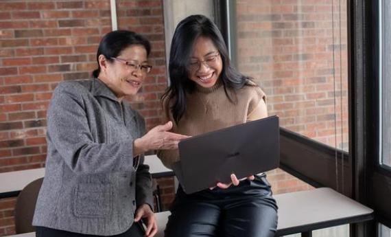 A Hamline student and her advisor looking at a laptop together and smiling