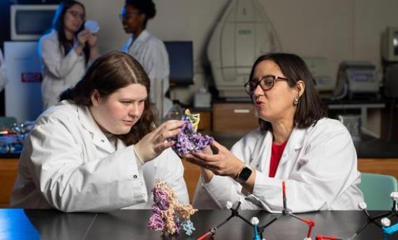 A Hamline student and professor in lab coats doing a classroom science experiment