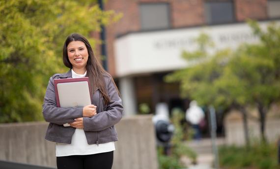 Hamline graduate student holding a computer