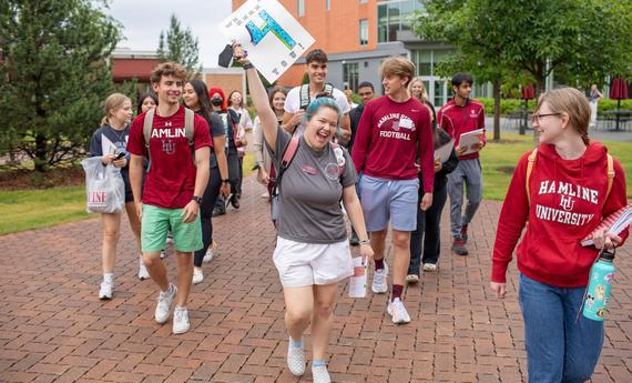 Students Walking on Hamline University holding a four sign
