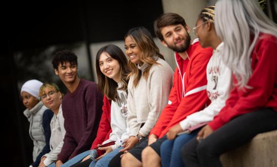 Diverse group of Hamline students sitting on a wall on campus