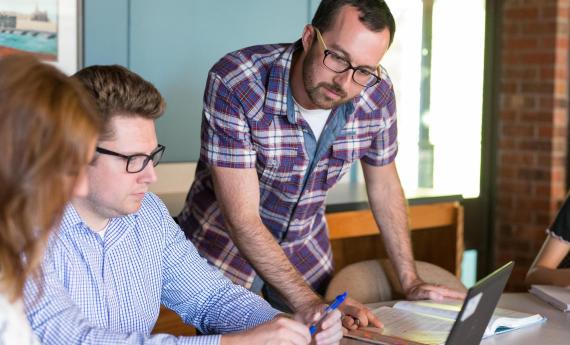 Man looking at laptop of grad student