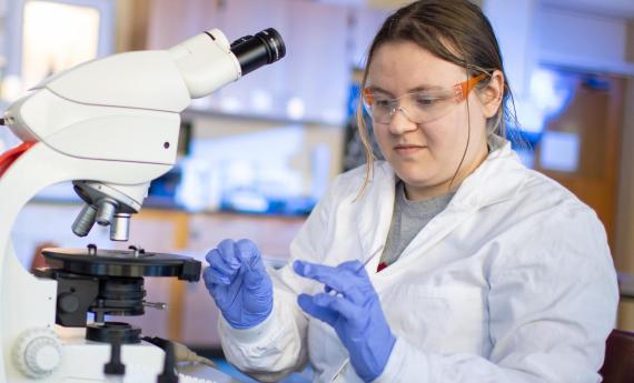 Student with microscope, forensics program