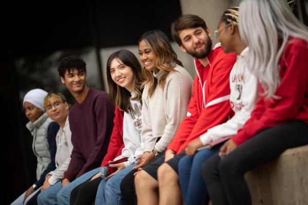 Diverse group of Hamline students sitting on a wall on campus