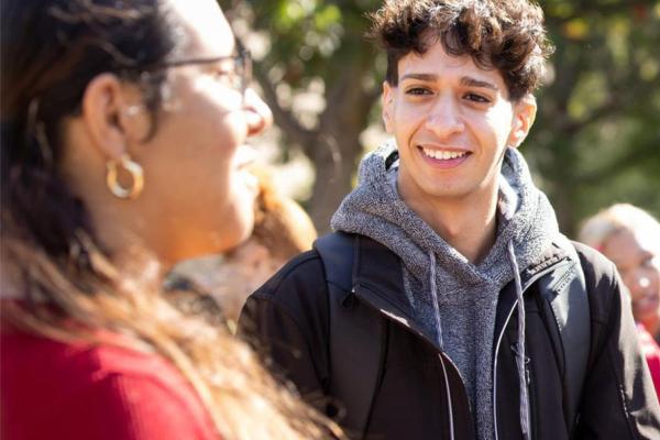 Hamline student in grey hoodie smiling at student with earrings