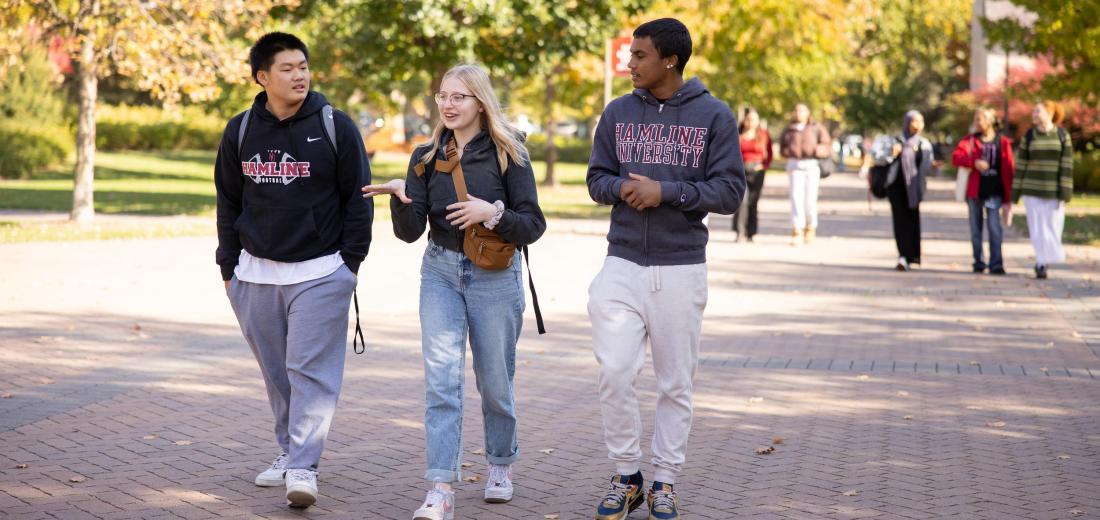 Three students walk on campus