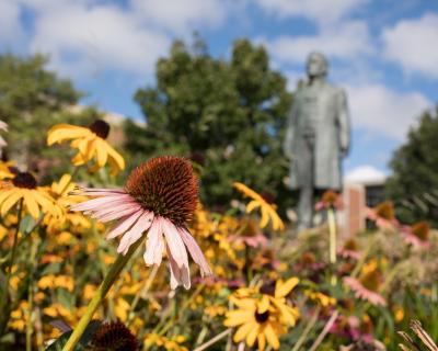 Flowers bloom near the Bishop Hamline statue