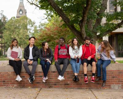 Students sitting on wall on campus