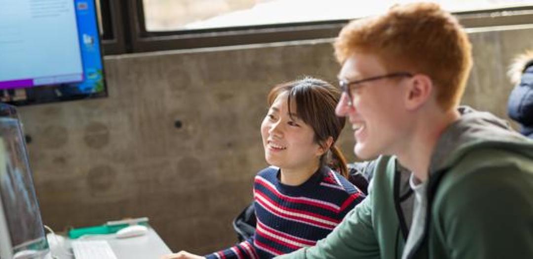 Two Hamline students in the classroom looking at a computer