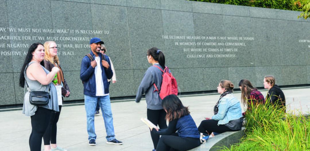 A group of Hamline students standing in front of an outdoor social justice display