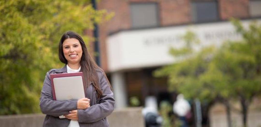 Hamline graduate student holding a computer