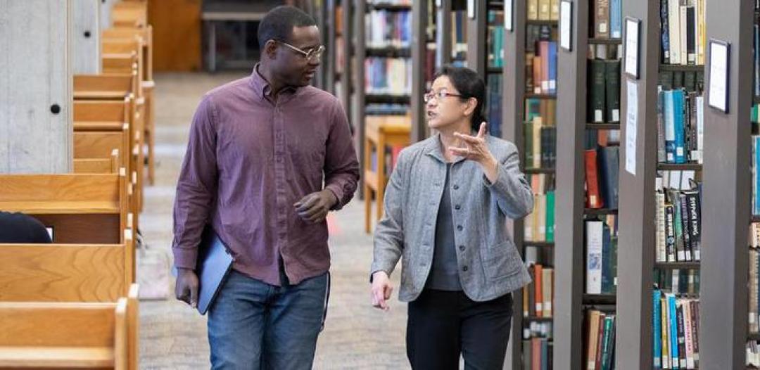 Hamline professor and student talking in the library