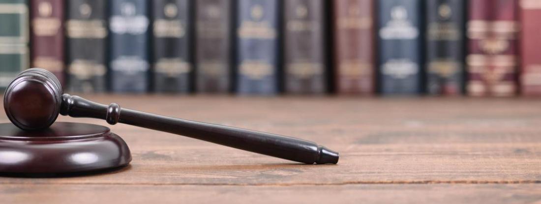 a gavel laying on a table with a row of law books in the background