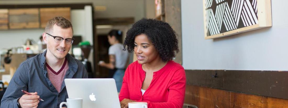 Two Hamline Students look to a computer in a coffee shop